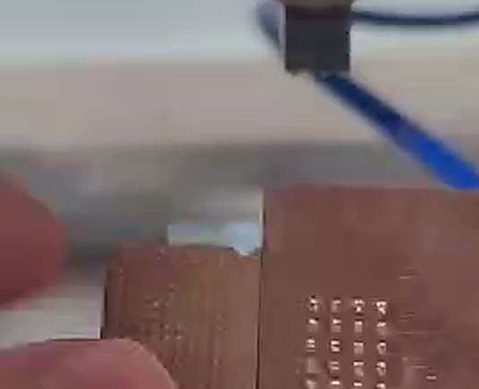 A copper foil transition tab welded by ultrasound, pulled aside to show the weld nugget